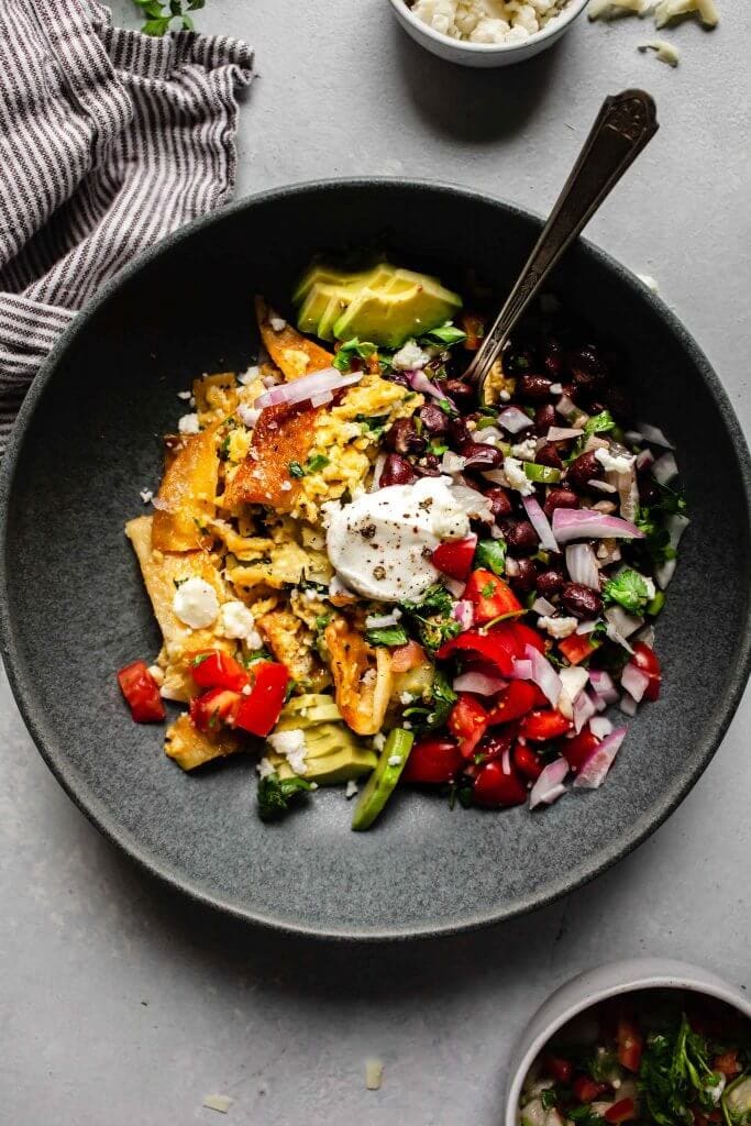 Migas in grey bowl topped with sour cream and pico.