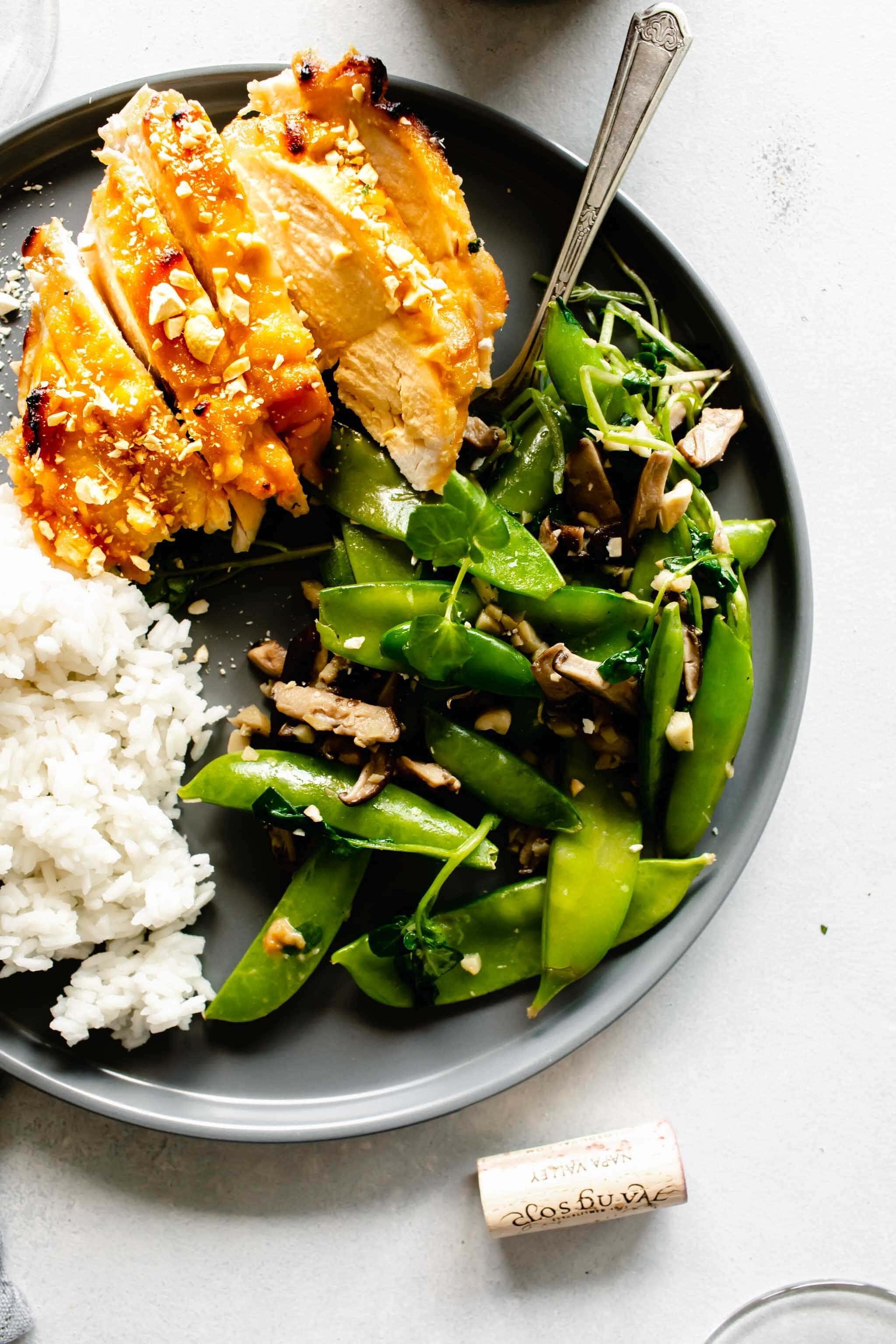 Miso chicken breast, sliced, served on grey dish with rice and green vegetables.