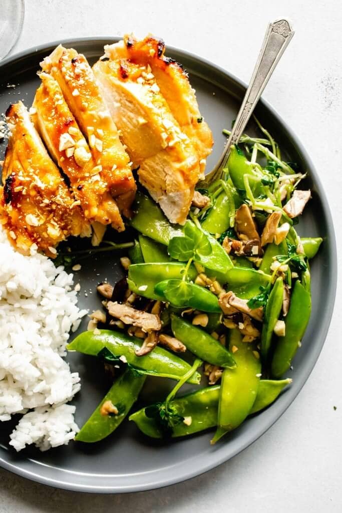 Miso chicken breast, sliced, served on grey dish with rice and green vegetables.
