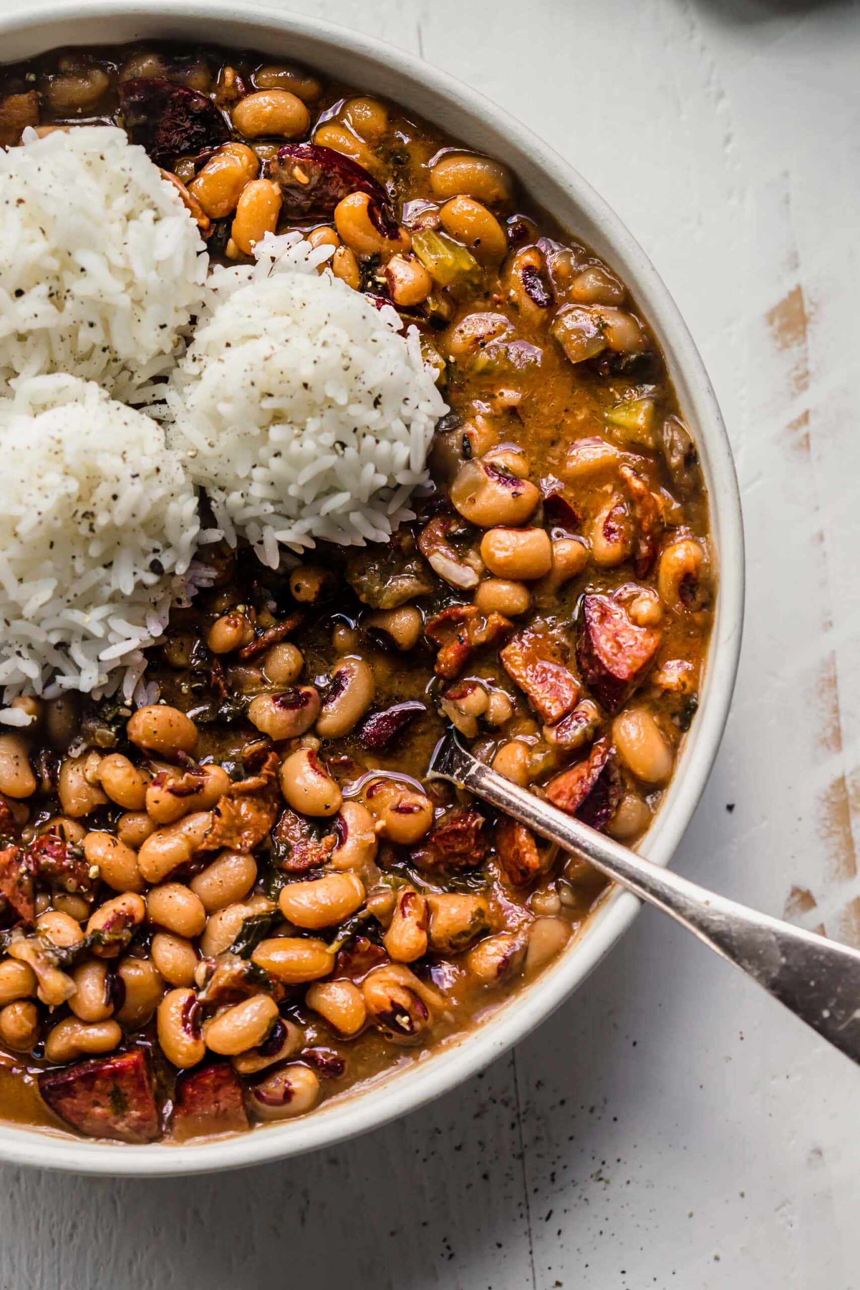 Overhead close up of black eyed peas in white bowl topped with scoops of rice.