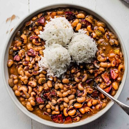 Black eyed peas in white bowl topped with scoops of rice.