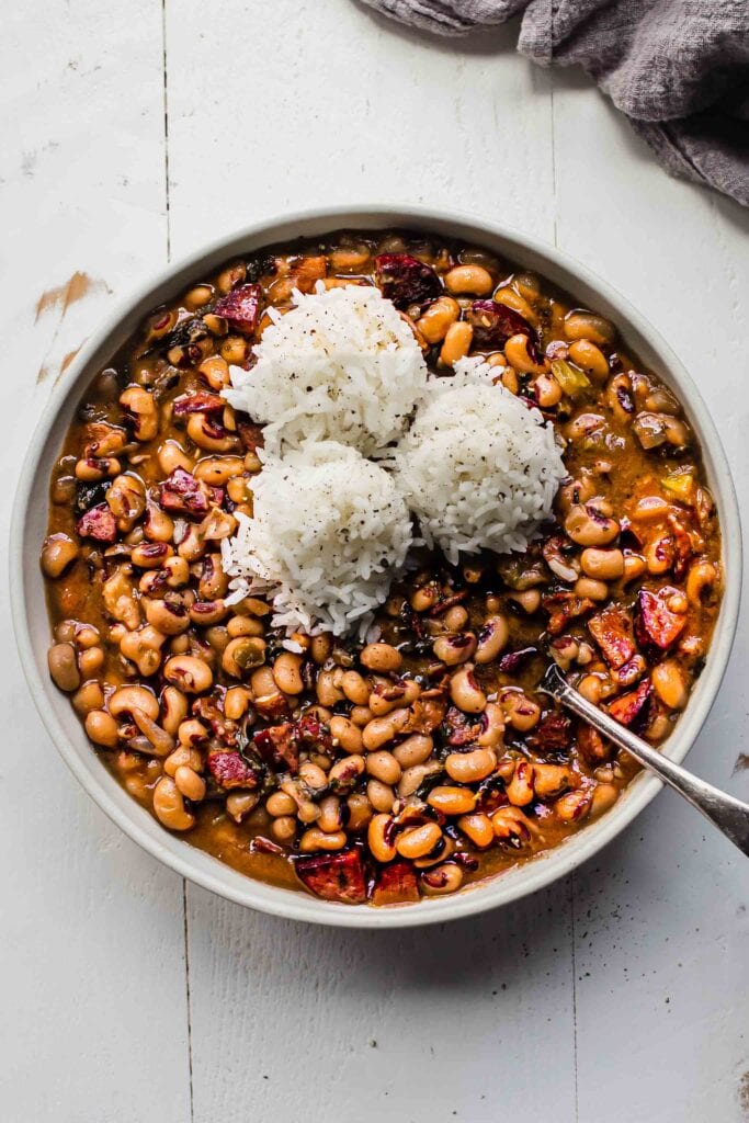 Black eyed peas in white bowl topped with scoops of rice.