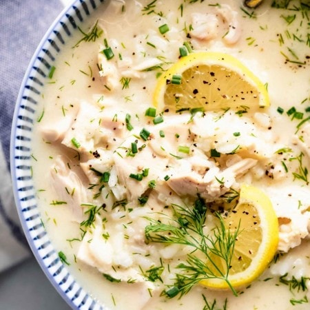 Bowl of avgolemono soup topped with lemons.