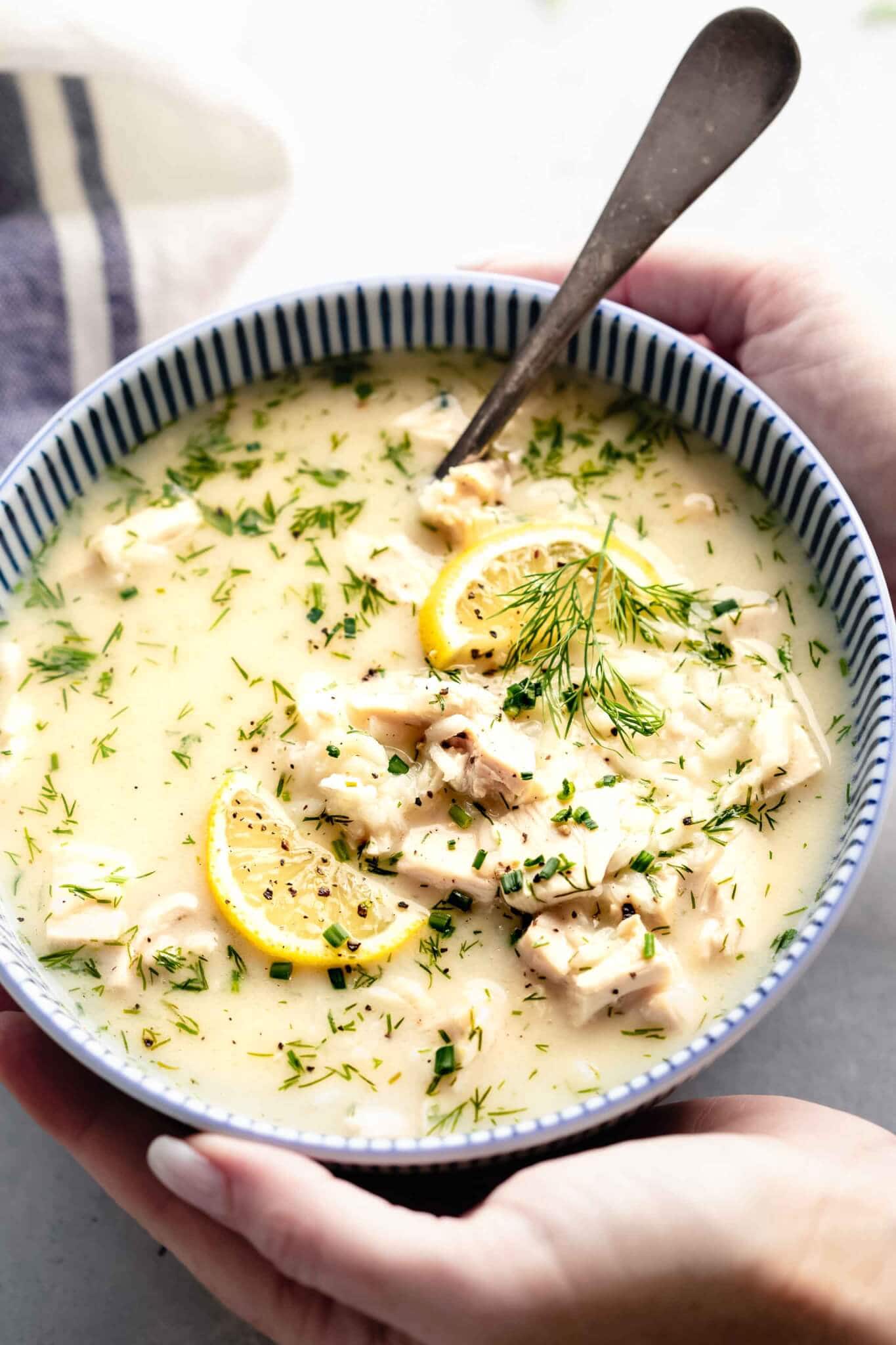 Two hands holding bowl of avgolemono soup. 
