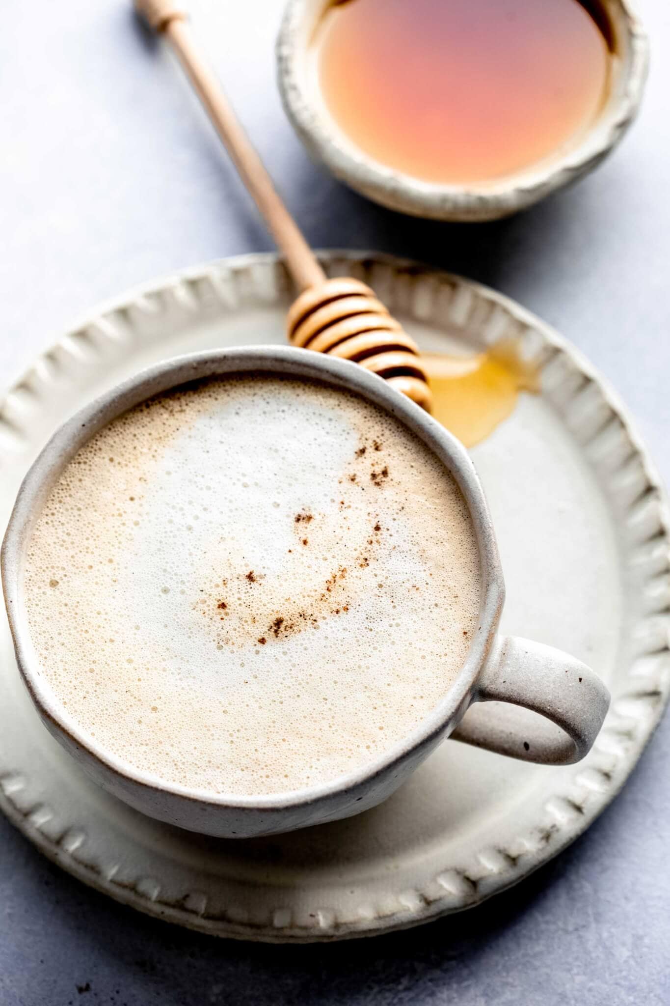 Side view of cardamom latte next to honey wand.