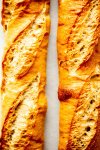 Two baguette loaves on white background.