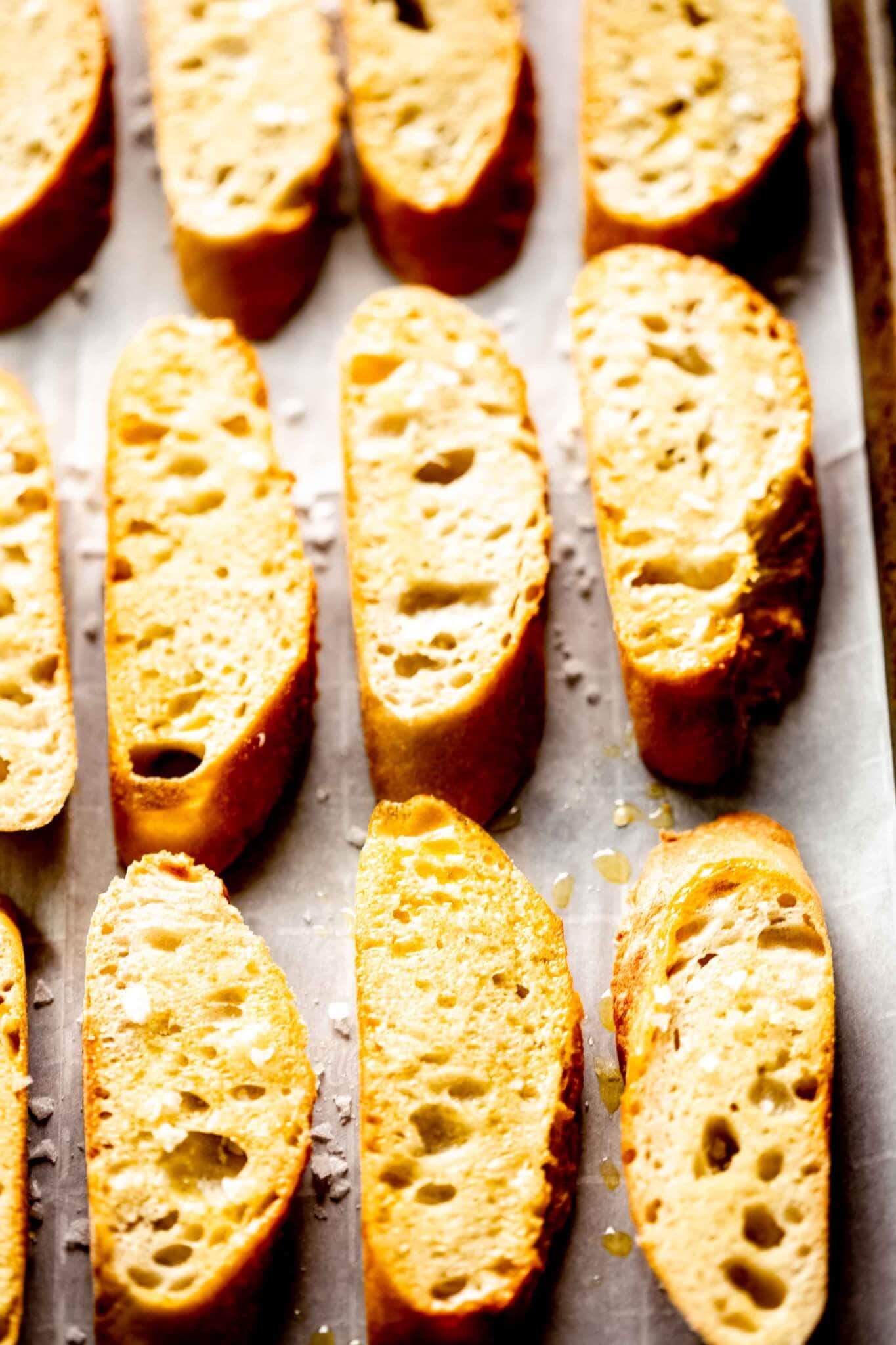 Side view of baguette slices on baking sheet.