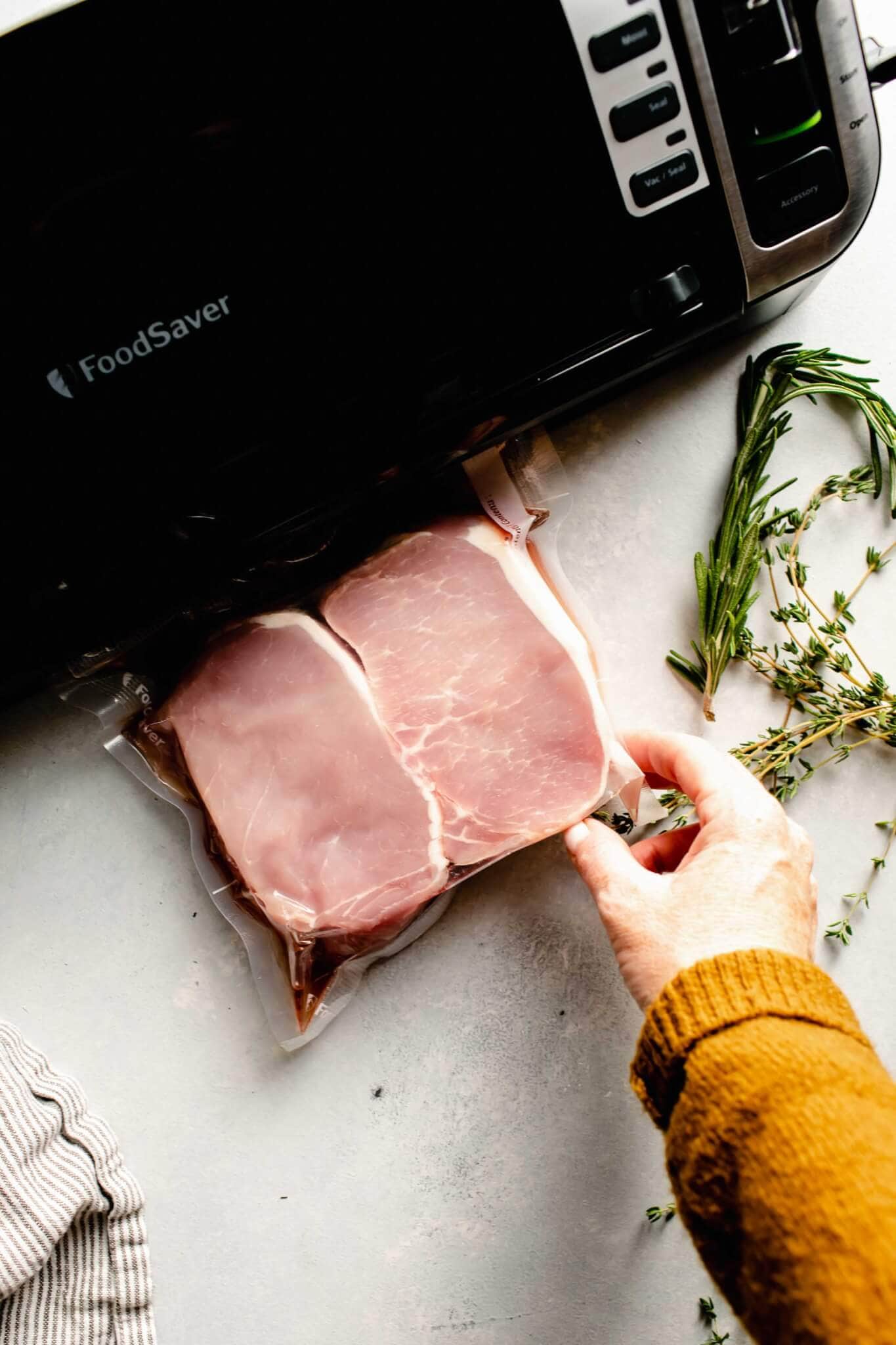 2 pork chops in foodsaver bag being sealed.