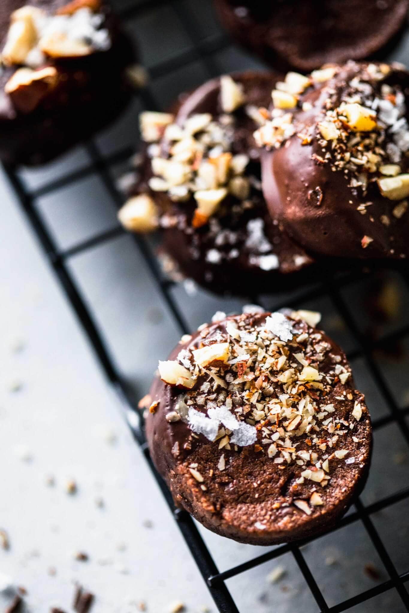 Closeup of chocolate dipped shortbread cookie topped with hazelnuts & sea salt. 