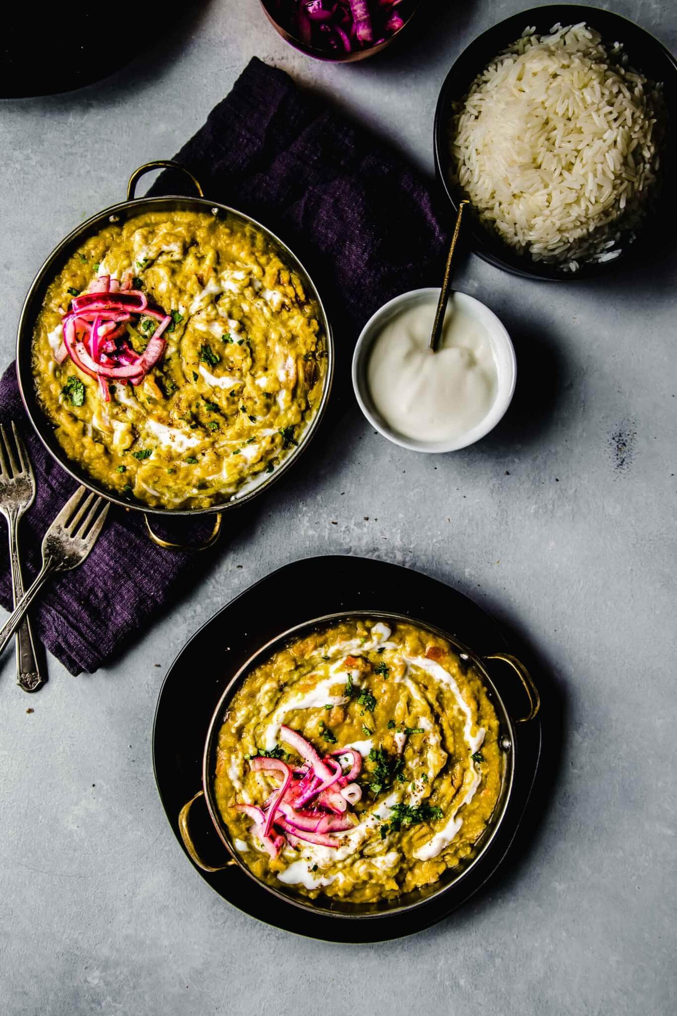 Overhead of two bowls of prepared instant pot dal next to bowl of rice and bowl of yogurt. 