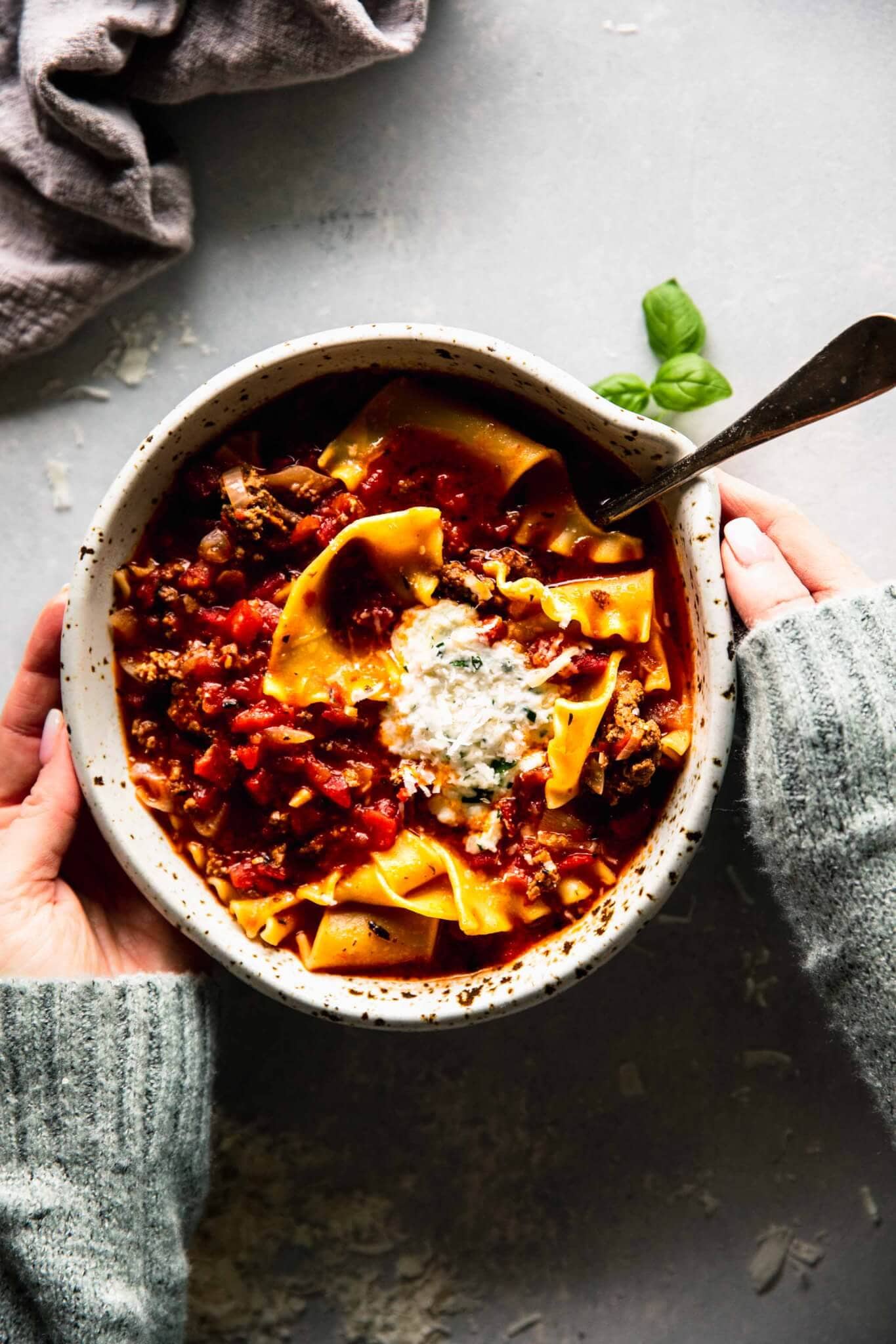 Two hands holding bowl of lasagna soup