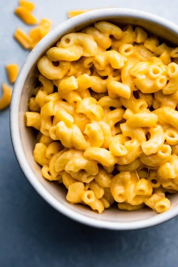 Overhead shot of bowl of mac and cheese on blue background.