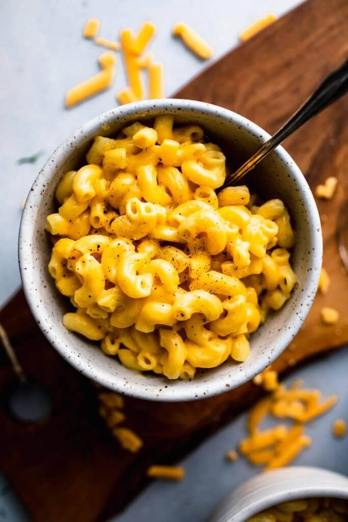 Overhead shot of bowl of mac and cheese in speckled bowl with fork.