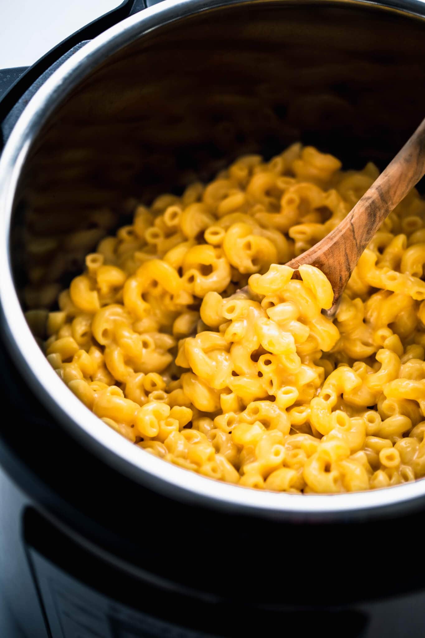 Cooked mac and cheese in the instant pot with wooden spoon.