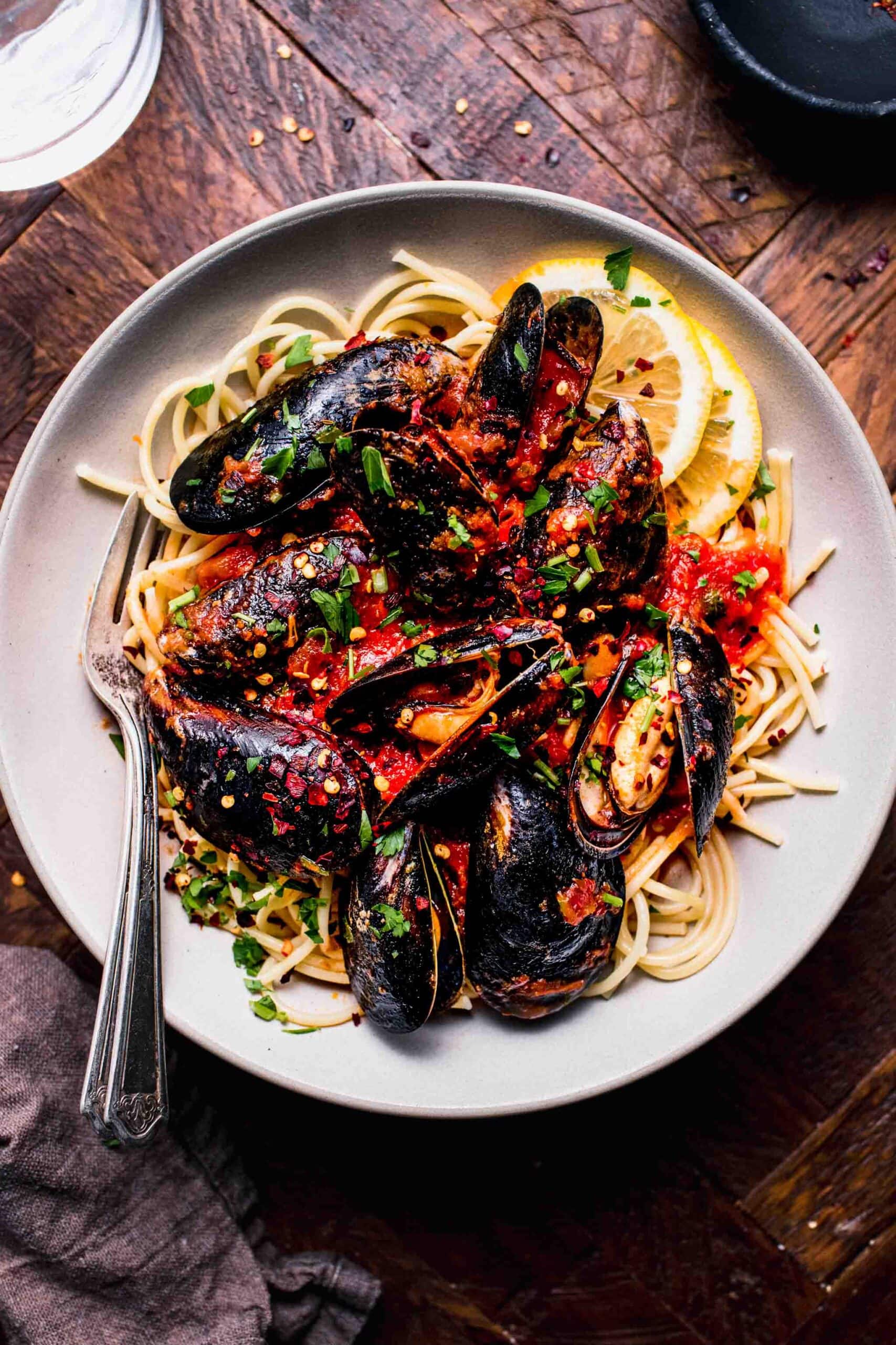 Mussels marinara served over bowl of spaghetti.