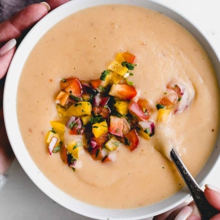 Two hands holding bowl of potato cheese soup.