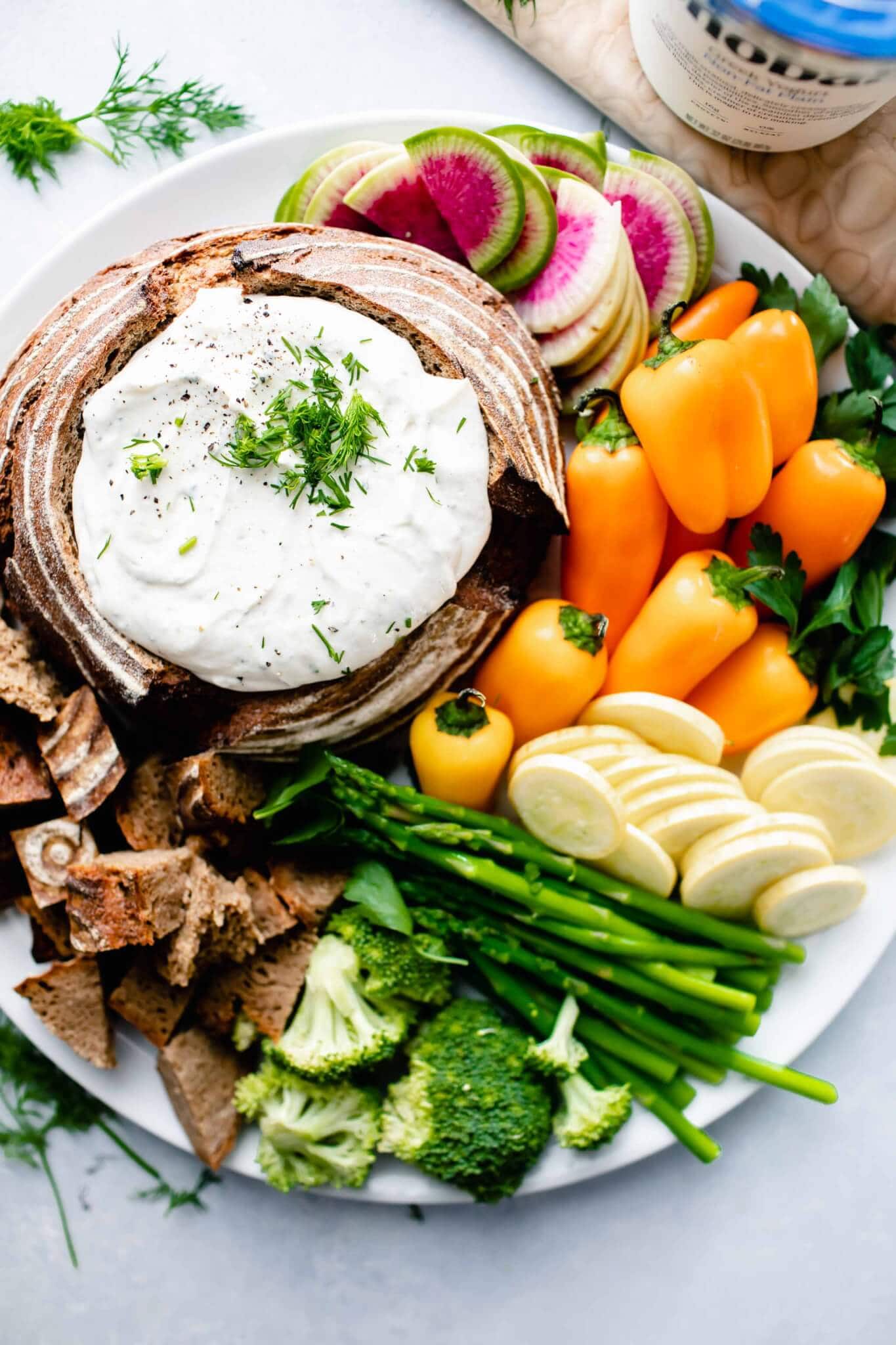 Overhead shot of ranch dip in bread bowl next to veggies.