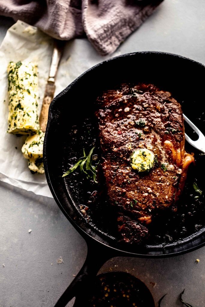 Sous vide ribeye steak in skillet topped with compound butter.