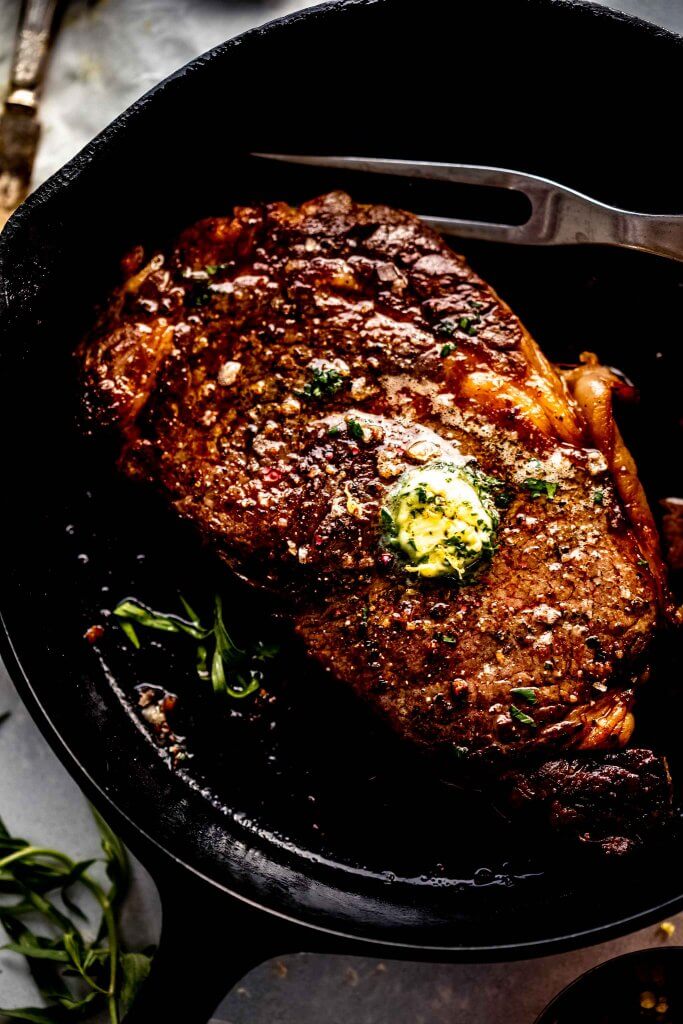 Sous vide ribeye steak in skillet topped with compound butter.