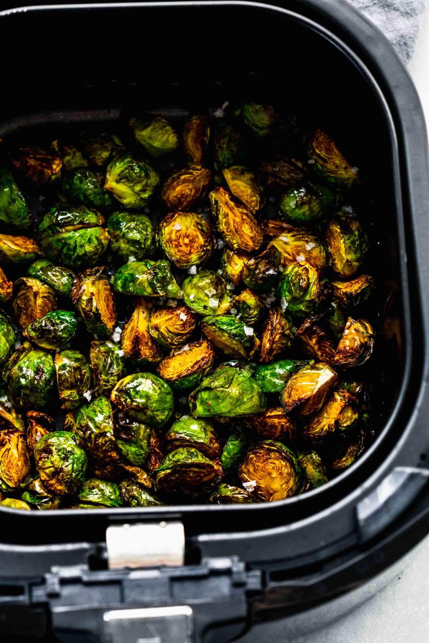 Cooked brussels sprouts in air fryer basket.