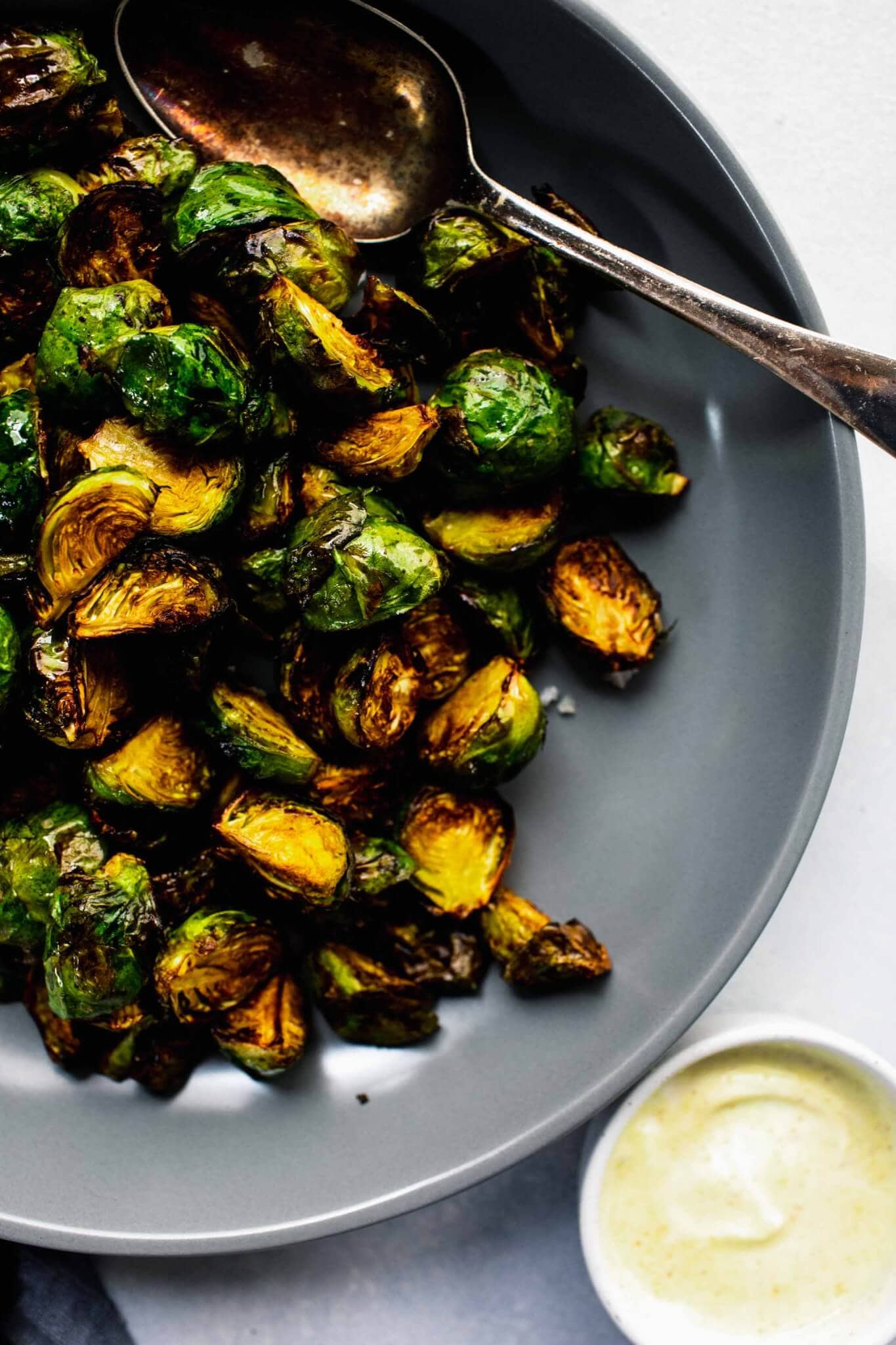 Over head shot of cooked brussels sprouts in grey bowl with spoon.