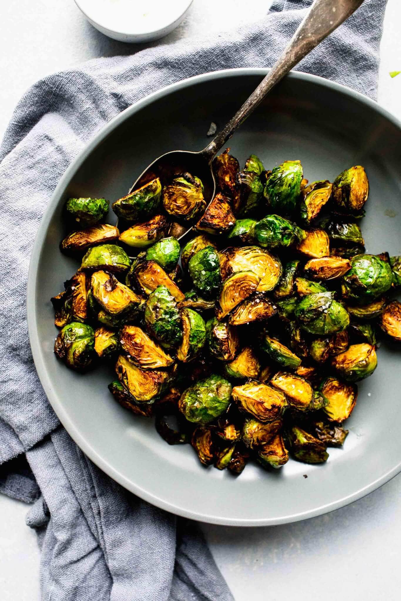 Over head shot of cooked brussels sprouts in grey bowl with spoon.