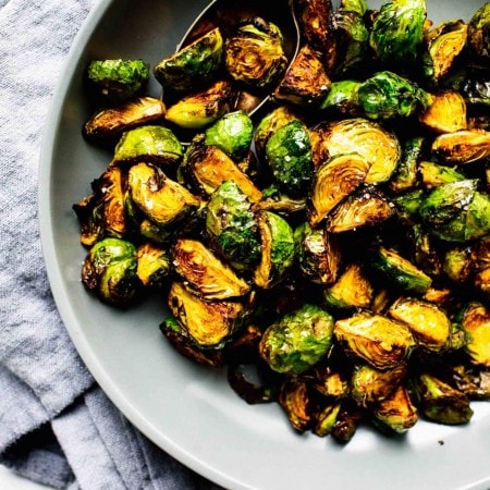 Over head shot of cooked brussels sprouts in grey bowl with spoon.