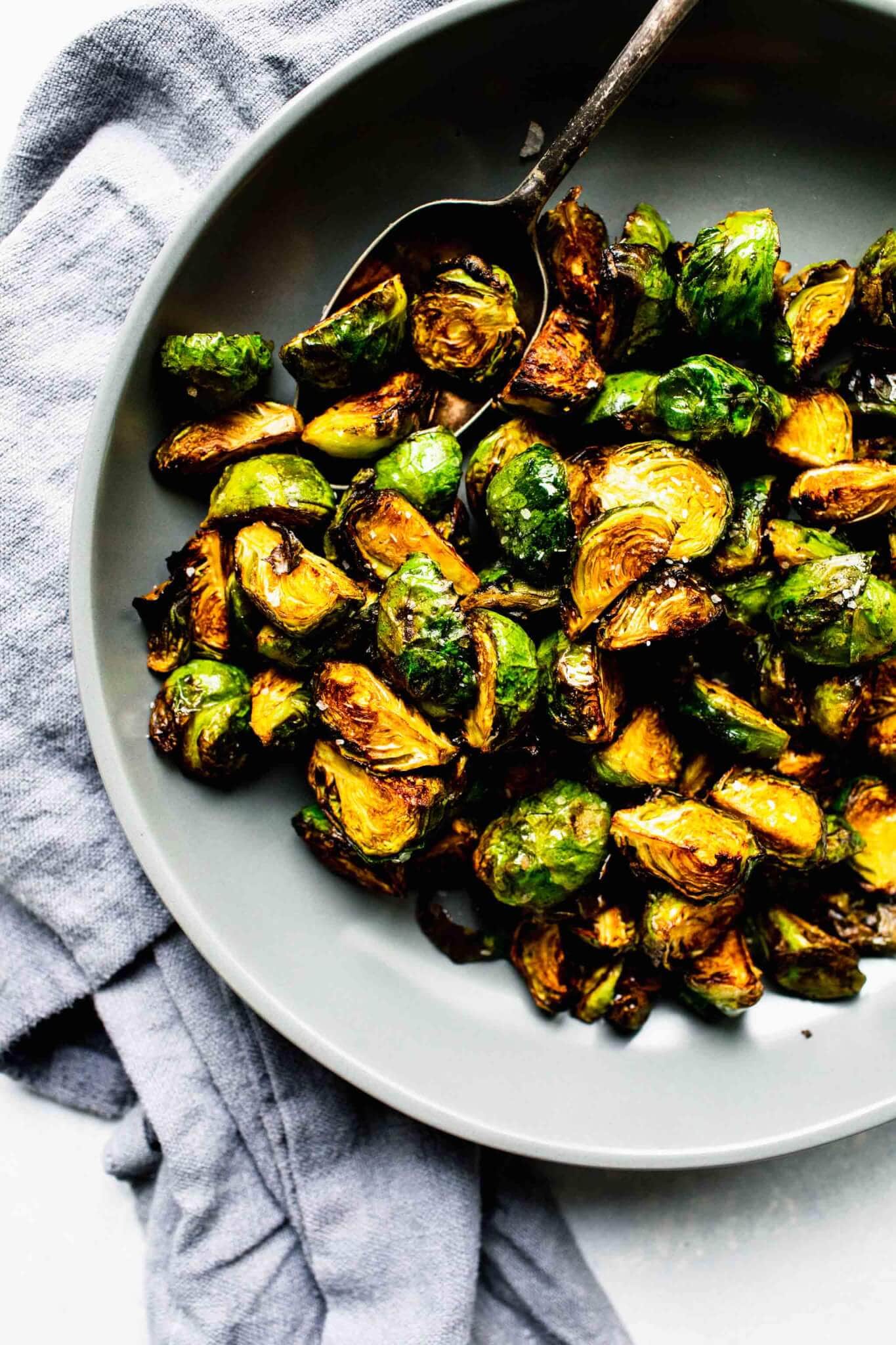 Over head shot of cooked brussels sprouts in grey bowl with spoon.