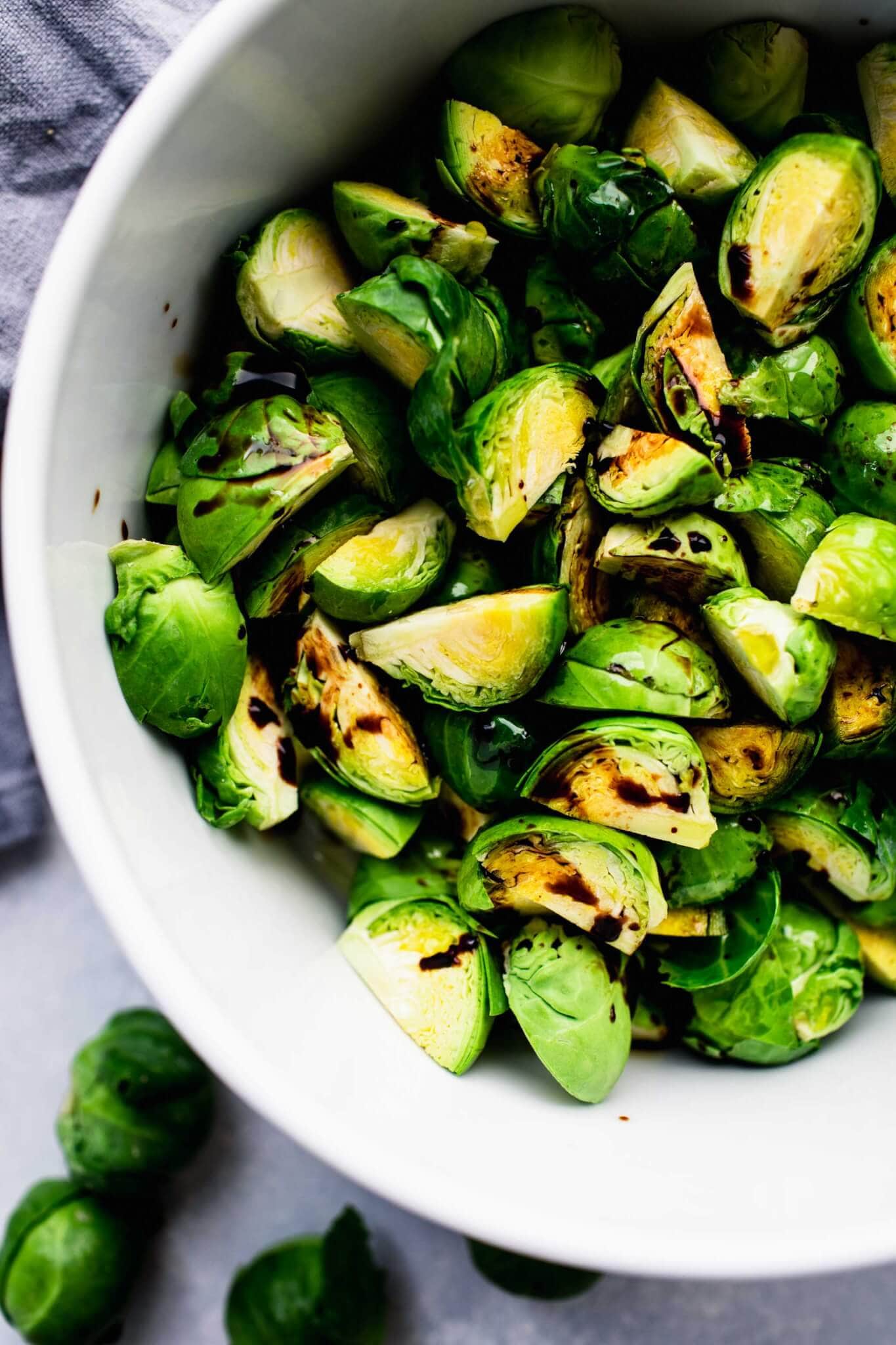 Brussels sprouts in white bowl drizzled with balsamic.