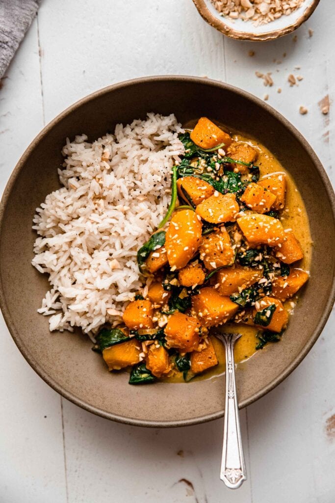 Bowl of butternut curry with rice and spoon.