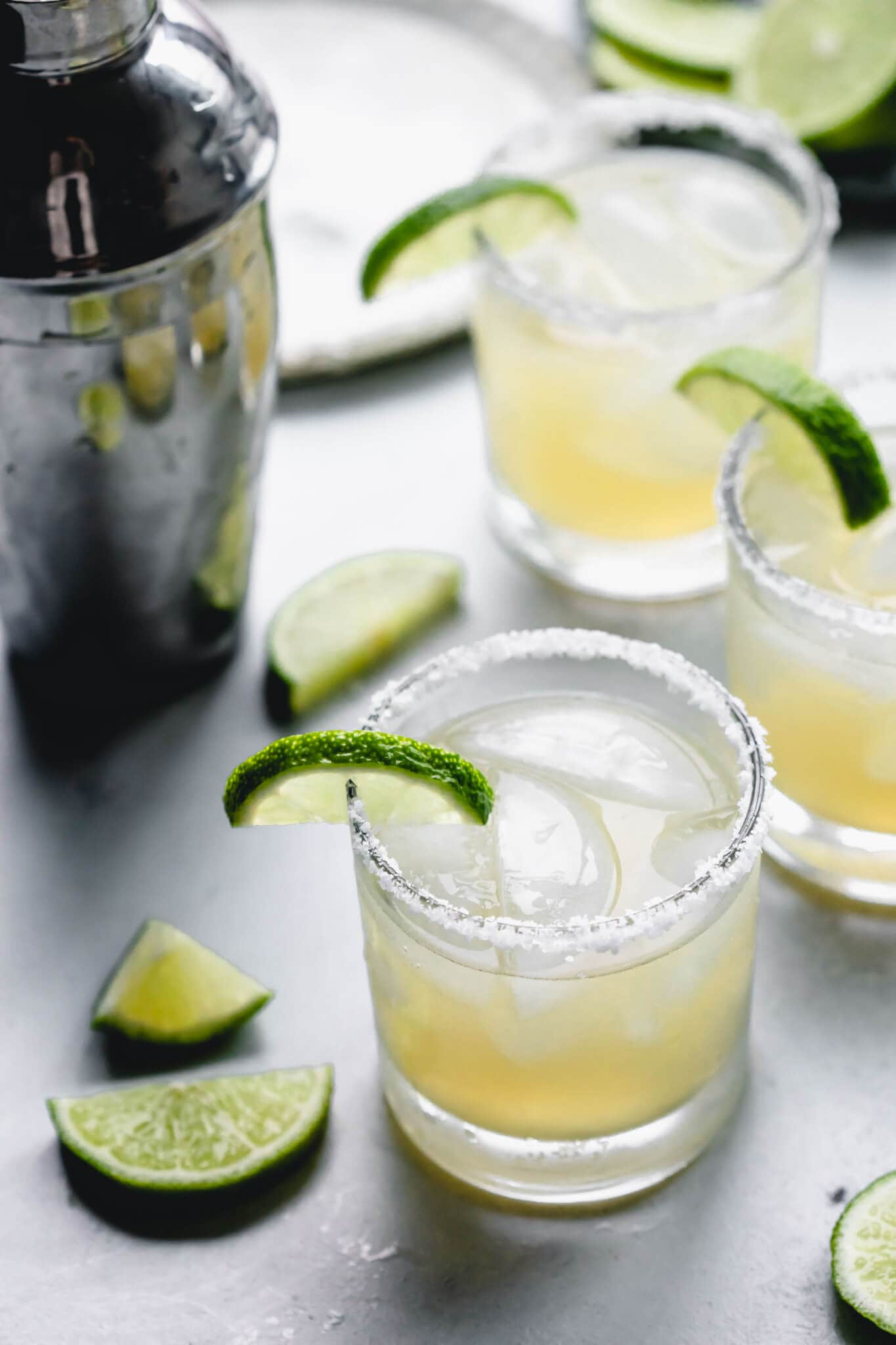 Side view of three elderflower margaritas next to cocktail shaker.