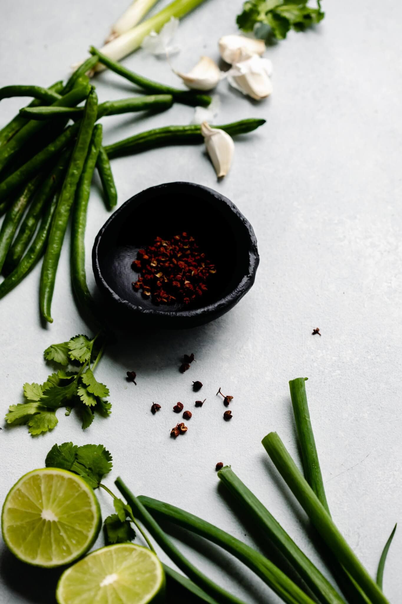 Ingredients for lamb stir fry laid on counter - limes, peppercorns, scallions, and garlic. 