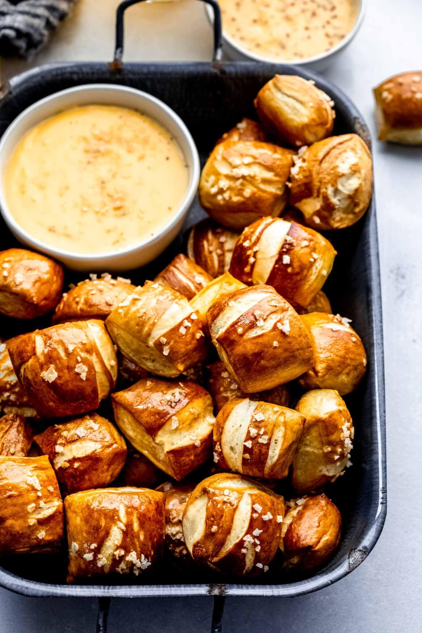 Side view of pretzel bites arranged in serving tray with bowl of cheese sauce.