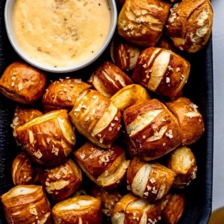 Overhead shot of pretzel bites in serving platter with small bowl of cheese sauce.