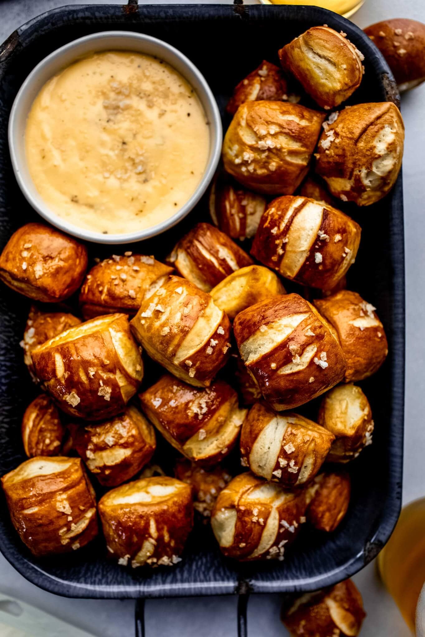 Overhead shot of pretzel bites in serving platter with small bowl of cheese sauce.