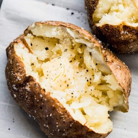 Overhead shot of air fryer baked potato split open and topped with butter.