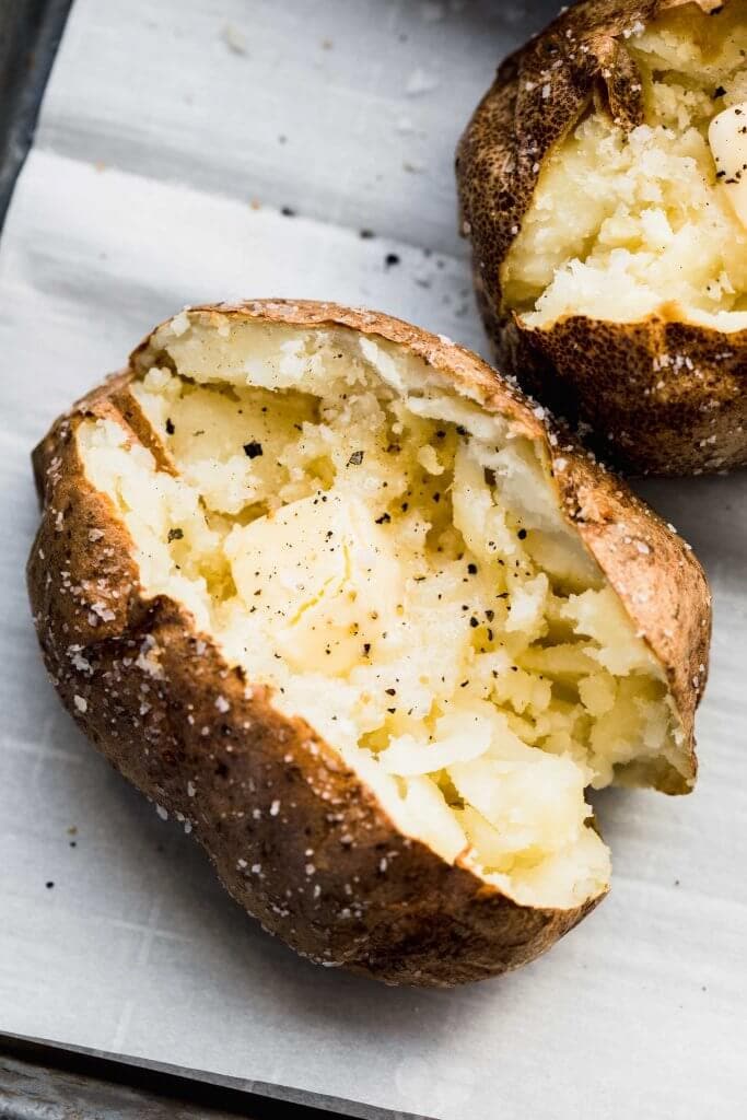 Overhead shot of air fryer baked potato split open and topped with butter.