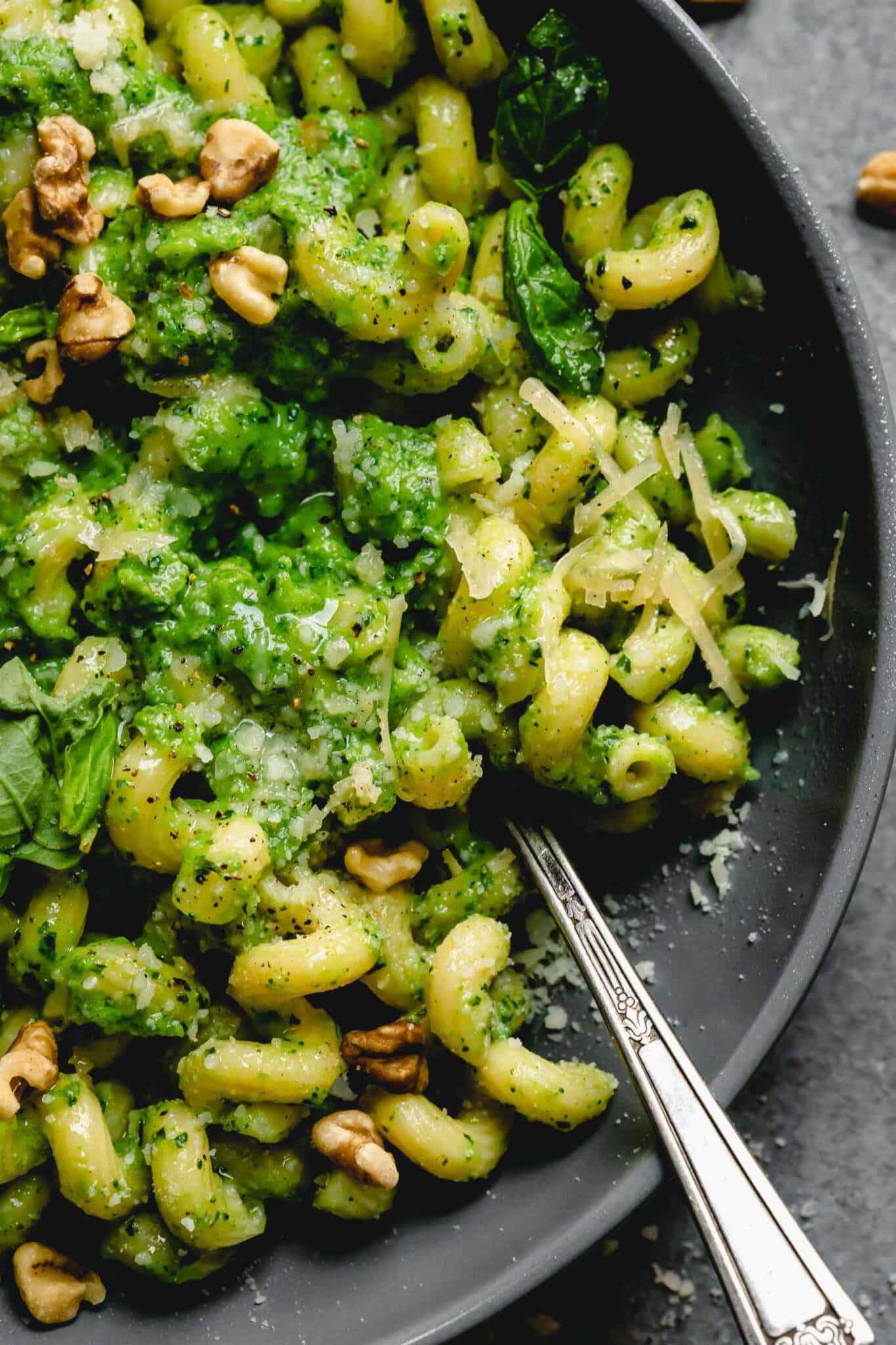Overhead shot of broccoli pesto pasta in grey bowl with spoon.