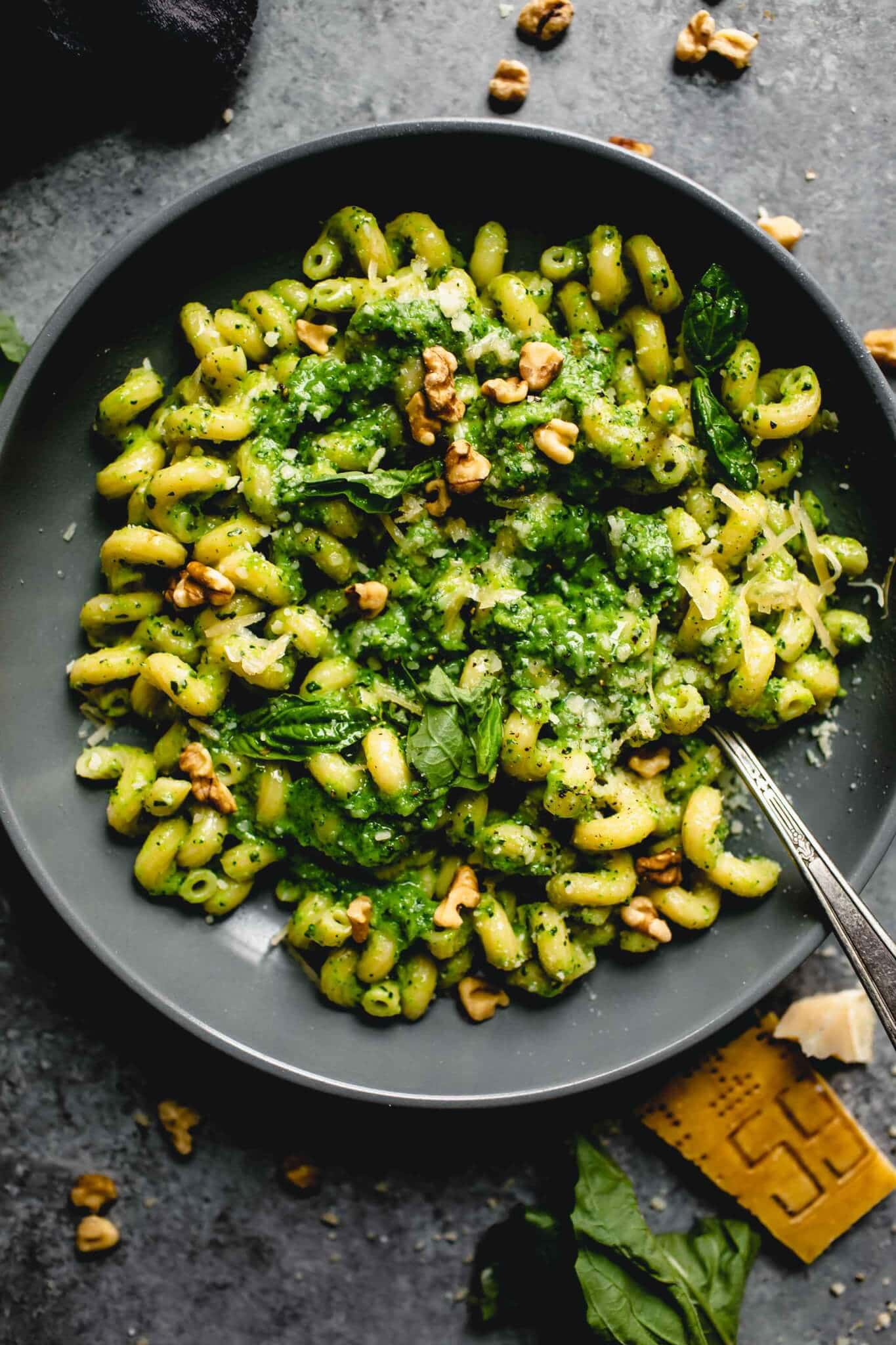 Overhead shot of broccoli pesto pasta in grey bowl with spoon.