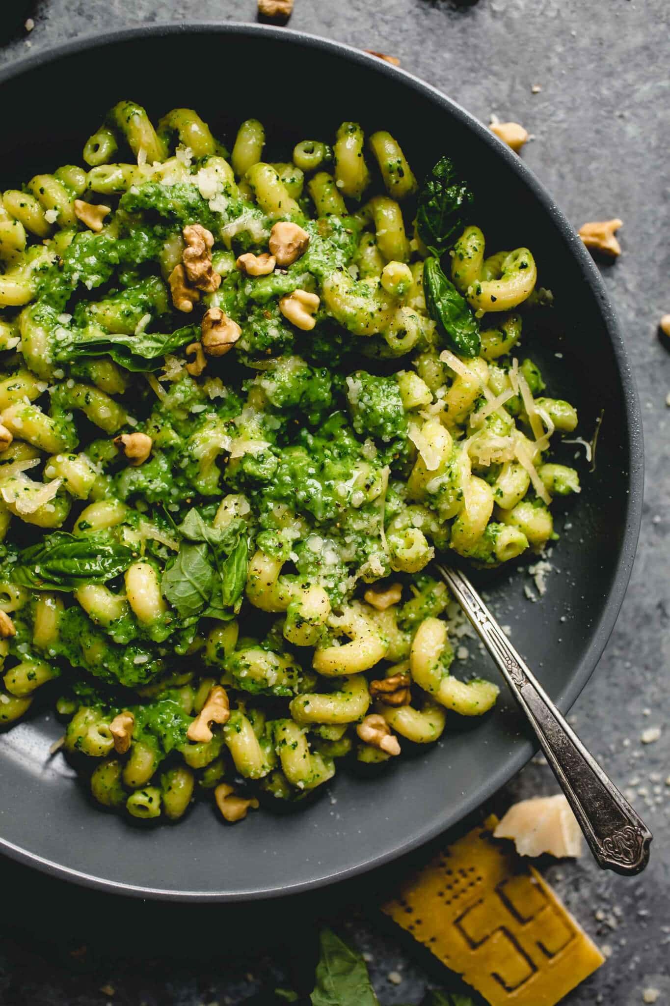Overhead shot of broccoli pesto pasta in grey bowl with spoon.