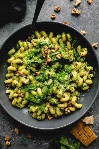 Overhead shot of broccoli pesto pasta in grey bowl with spoon.