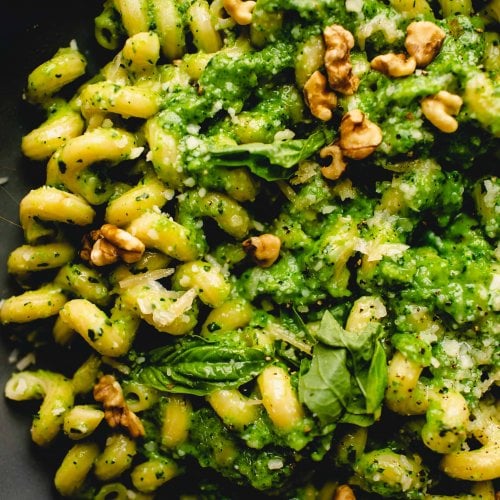 Overhead close up of bowl of pasta tossed with broccoli pesto.