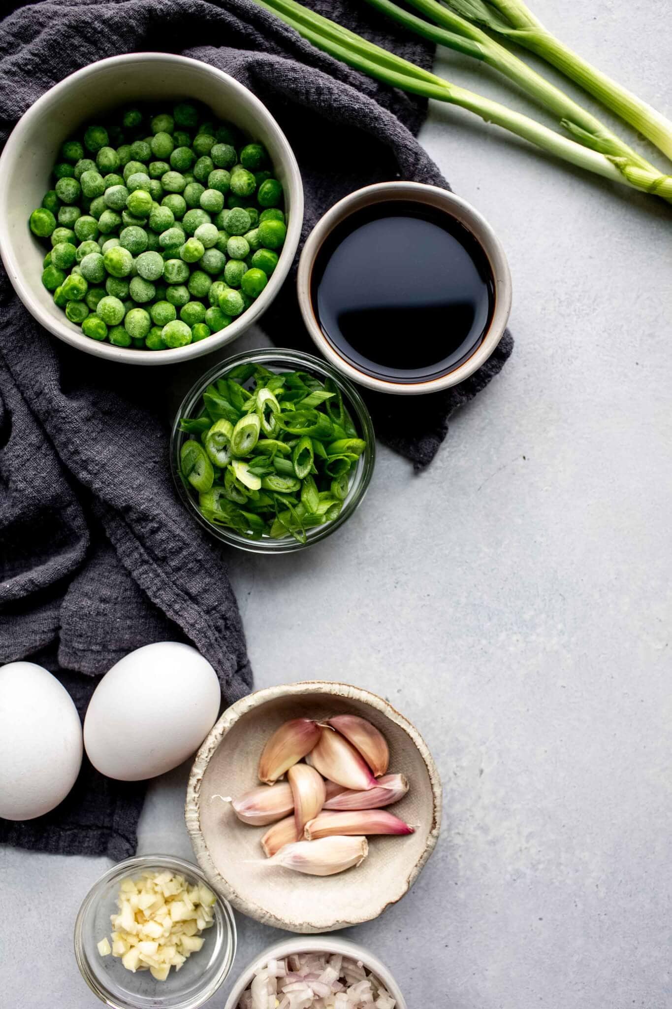 Ingredients for cauliflower fried rice laid out on concrete countertop .