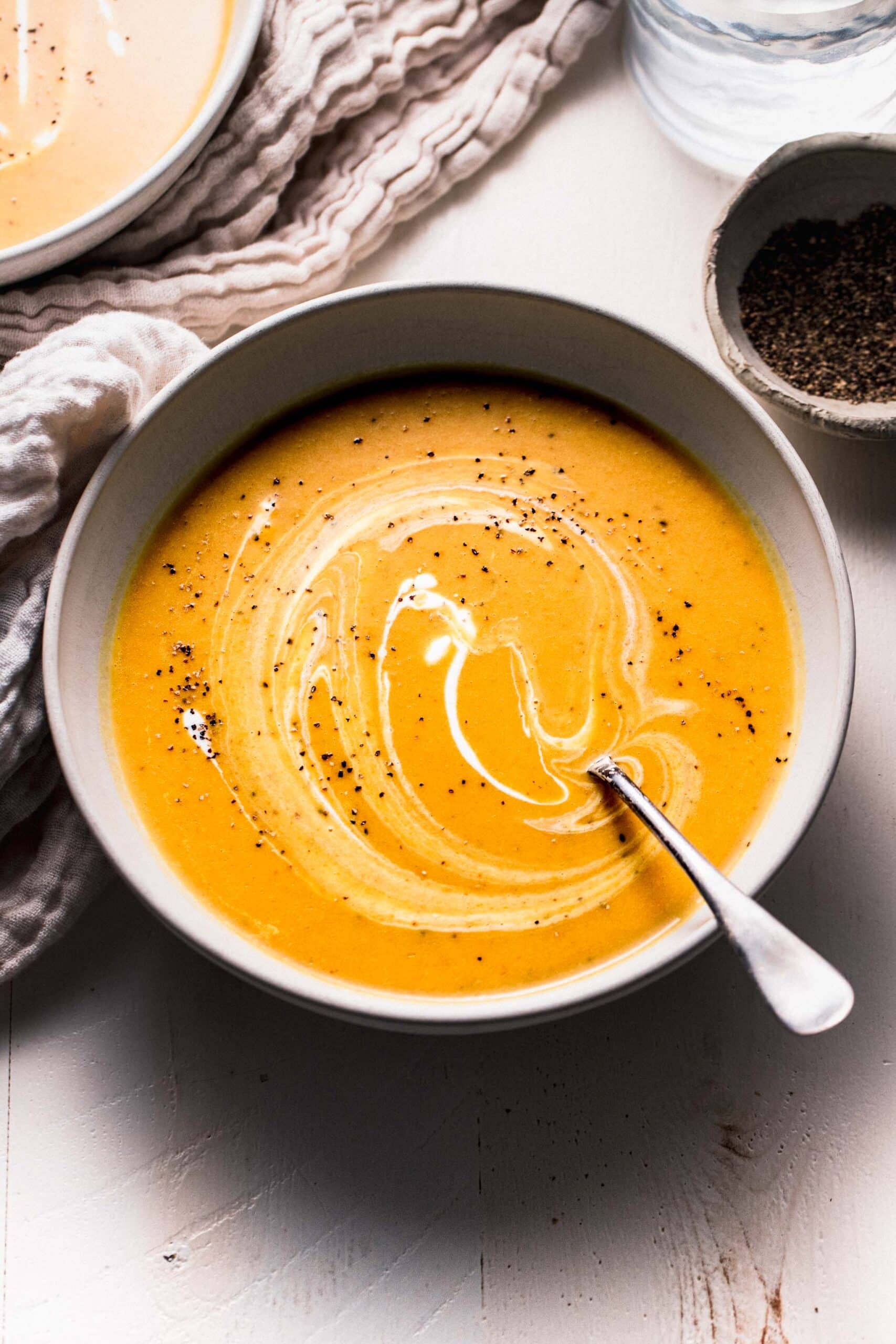 Side view of curried butternut squash soup in bowl with swirl of yogurt on top.