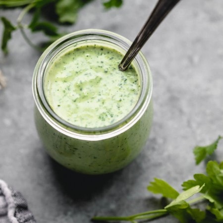 Small jar of green goddess dressing with spoon