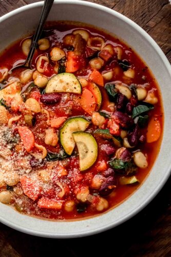 Overhead close up of bowl of minestrone on wood background.