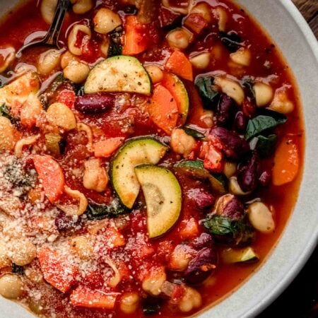 Overhead close up of bowl of minestrone on wood background.