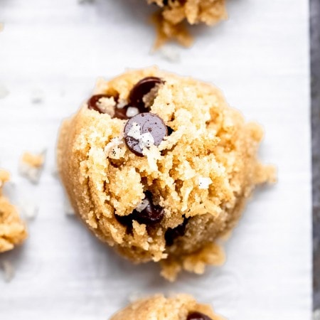 Overhead close up of cookie dough bites on parchment lined baking sheet.