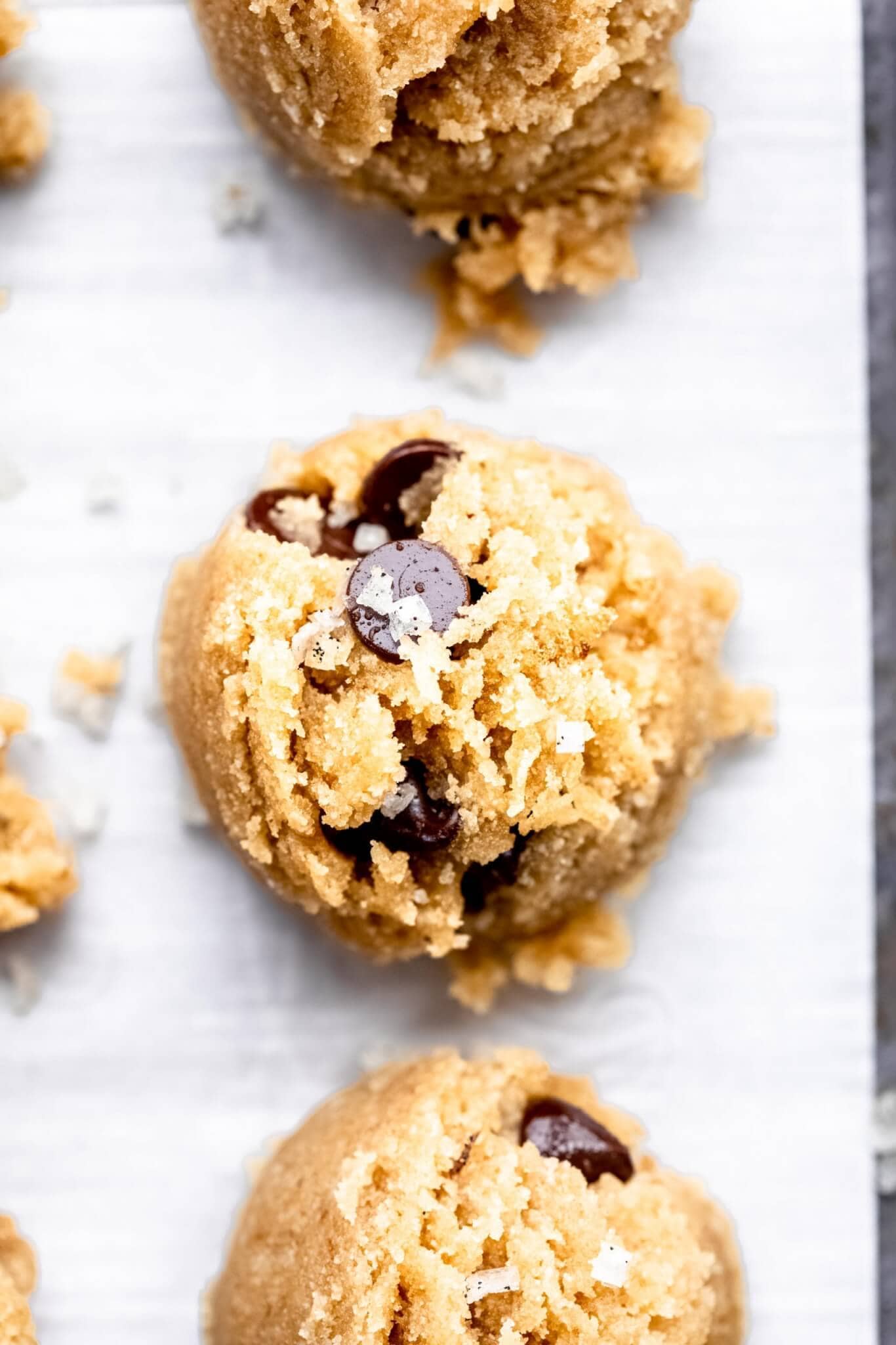 Overhead close up of cookie dough bites on parchment lined baking sheet.