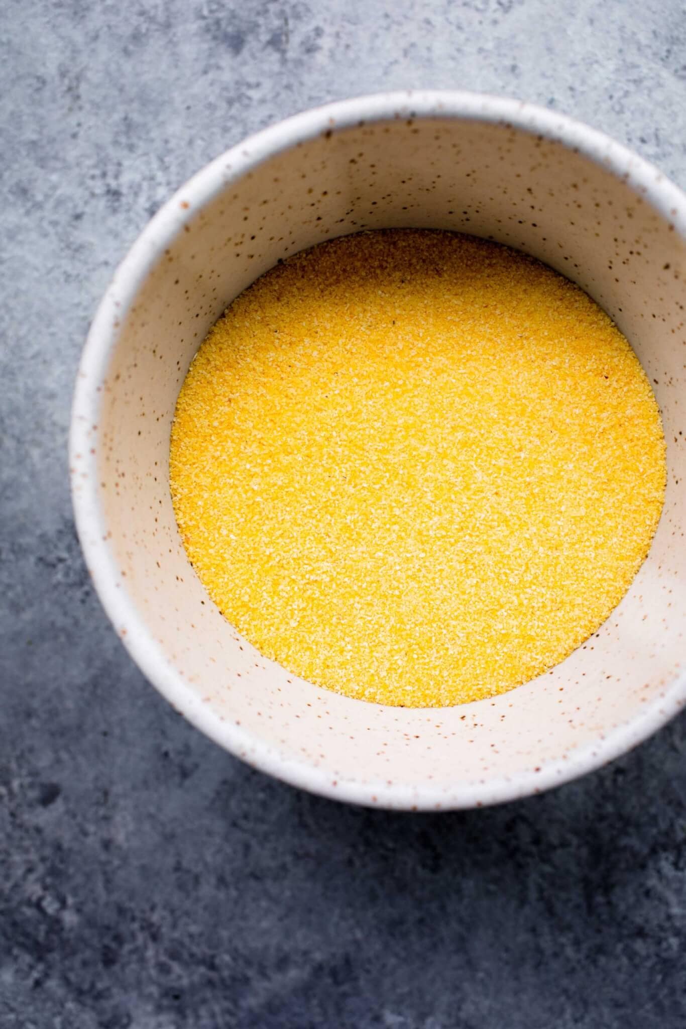 Uncooked polenta in small bowl.